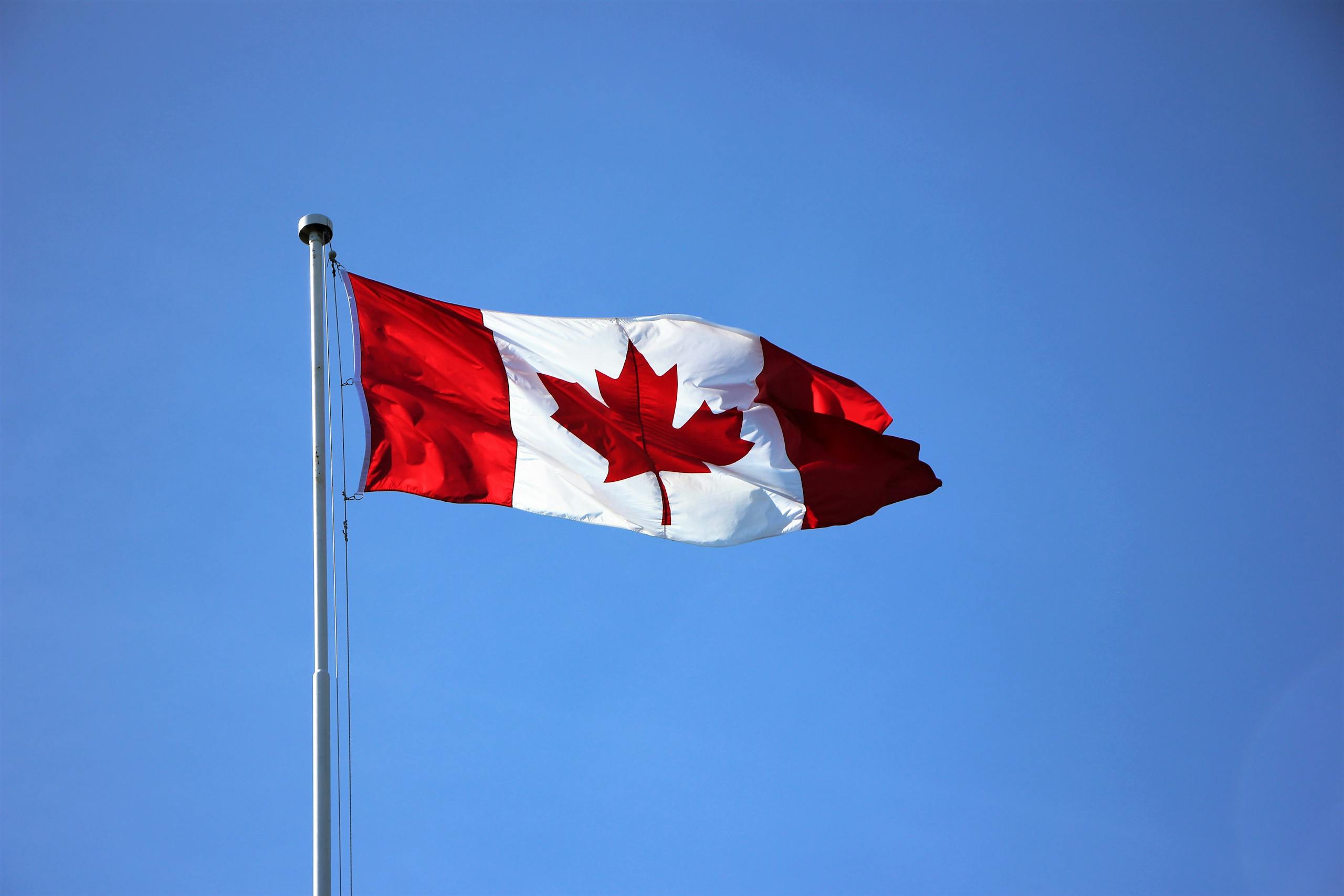 Canadian flag waving proudly against a clear blue sky in Victoria, BC.