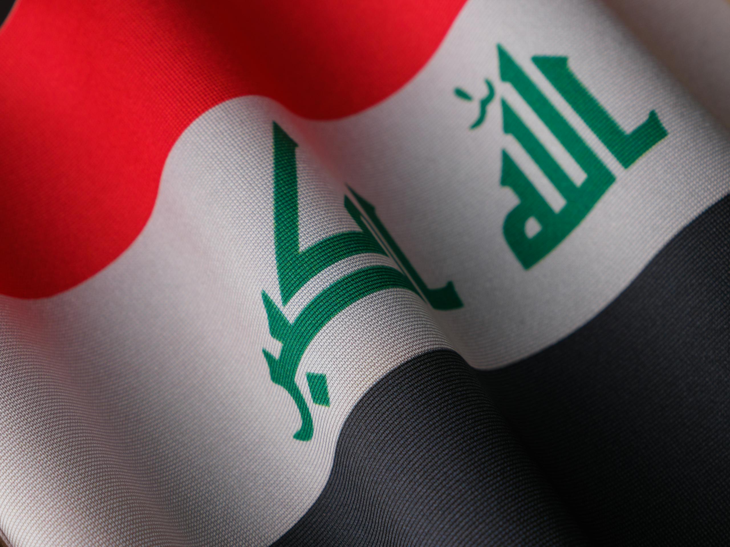 Detailed fabric texture of Iraq's national flag, showcasing patriotic symbols.