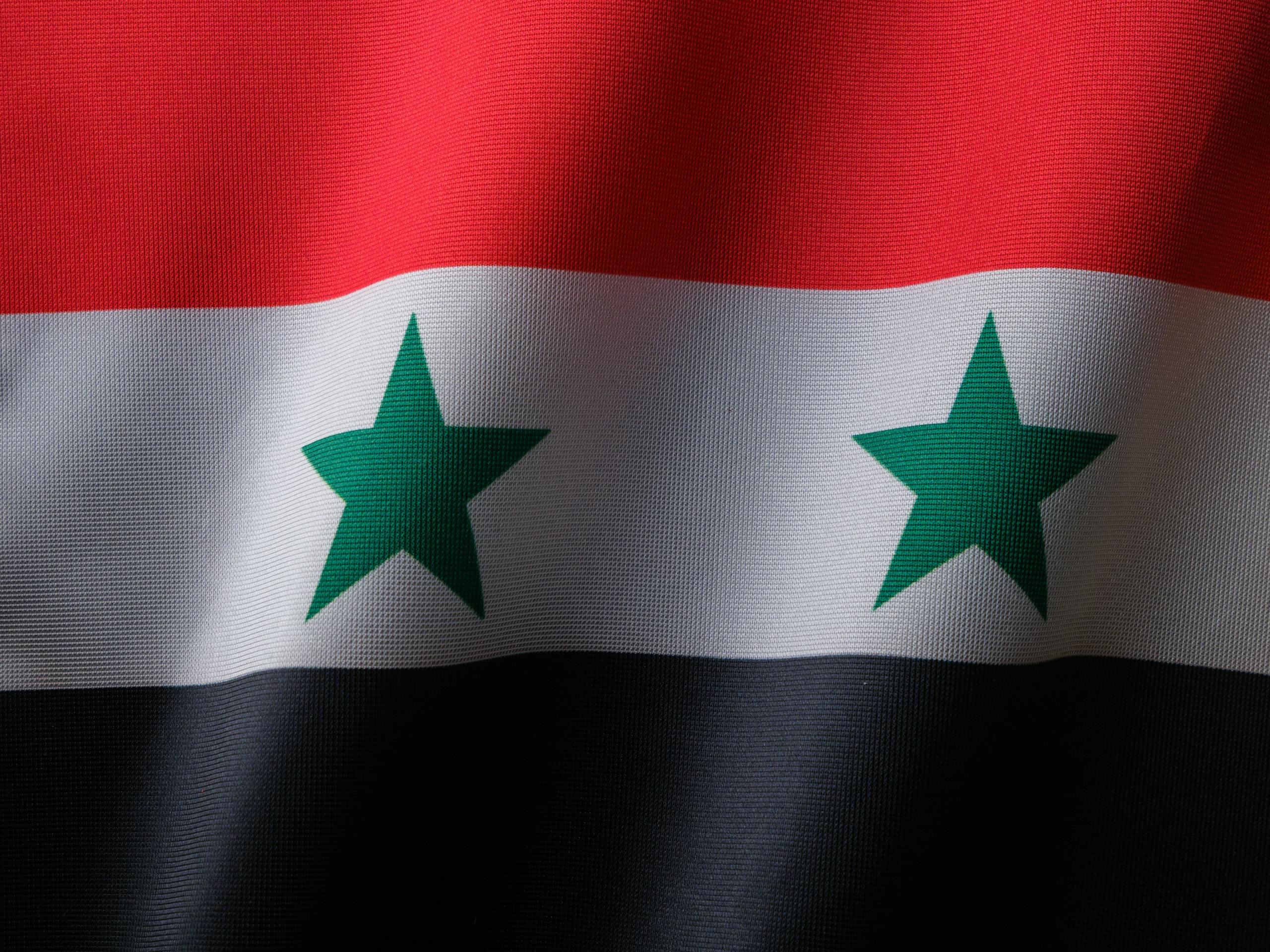 High-quality close-up of the Syrian national flag with textile texture.