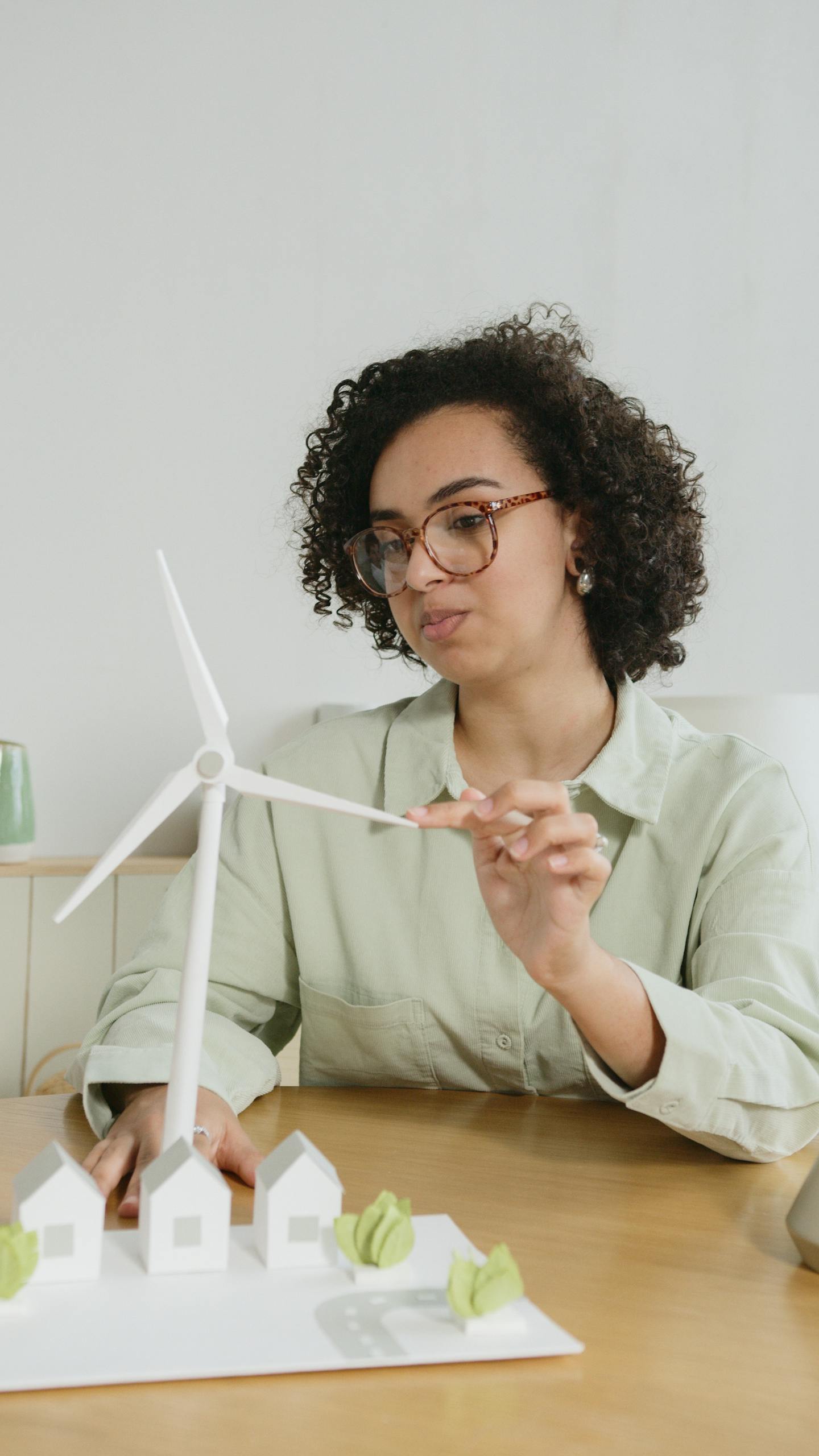 Woman demonstrating a miniature wind turbine model, focusing on renewable energy education.